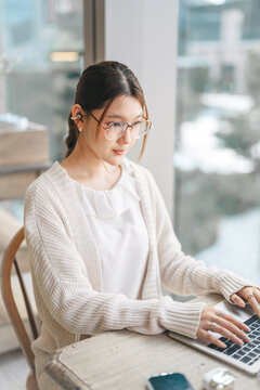 Beautiful young adult business asian woman working on laptop at indoor cafe relax living freelance with modern technology