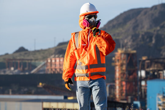 Mining worker in protective gear adjusting a respirator at an outdoor mining site