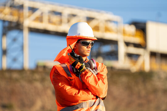 Industrial worker in safety gear, speaking into a radio at an outdoor worksite