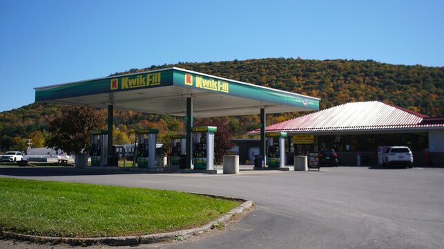 Susquehanna, Pennsylvania, U.S.A - Oct 18, 2026 - A Kwik Fill gas station with green and yellow canopies, situated near a convenience store and rolling hills with fall foliage