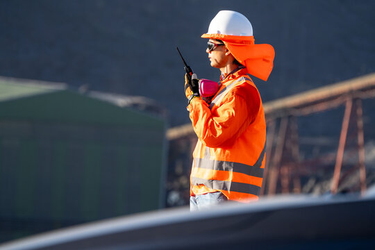 Mining worker in high-visibility gear, communicating by radio at industrial site