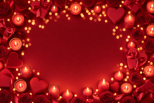 A top down view of a romantic Valentines Day setting featuring vibrant red roses glowing candles and heart shaped gift boxes arranged around an empty central space on a rich red background
