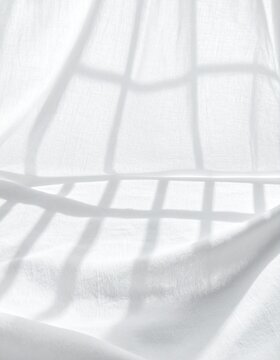 Soft window grid shadow falling across white cotton cloth, minimal overhead flat lay with copy space