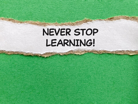 Never Stop Learning Quote on Torn White Paper Strip Over Green Background