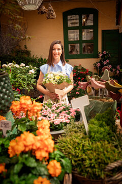 Smiling small business owner florist holding a flower bouquet and standing in a flower shop