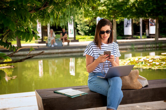 Smiling female freelancer working remotely on a laptop outdoors