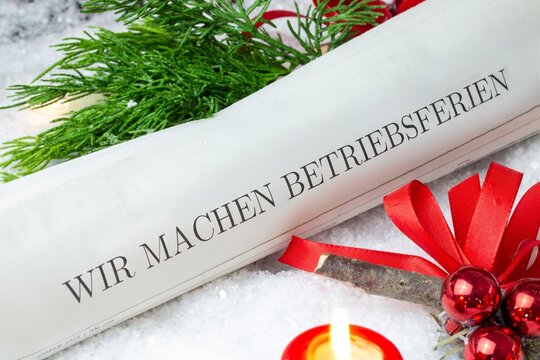 Betriebsferien zur Weihnachtszeit: Zeitung mit Text WIR MACHEN BETRIEBSFERIEN mit weihnachtlicher Dekoration (digital bearbeitet)