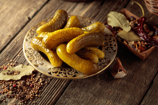 Pickled cucumbers with ingredients on an old wooden table.