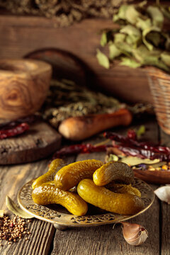 Pickled cucumbers with ingredients on an old wooden table.