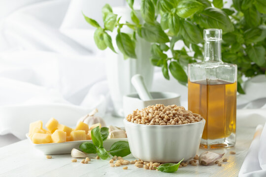 Ingredients for making Pesto sauce on a white wooden table.