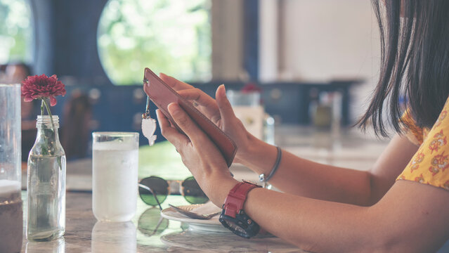 Close-up of Woman hand uses smartphone for mobile communication, during relaxation at restaurant cafe table. Digital lifestyle and internet connection concept