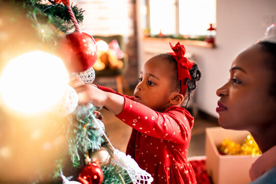 Girl decorating a christmas tree with woman at home
