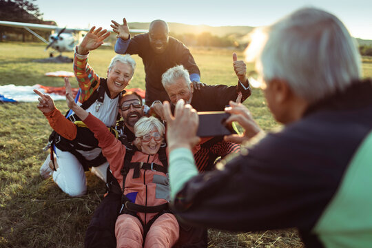 Seniors celebrating after skydiving as friend takes photo