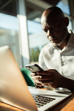 Man checking smartphone next to open laptop indoors