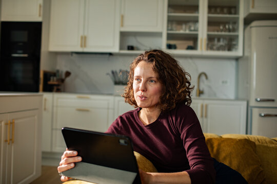 Woman talking on tablet in home kitchen