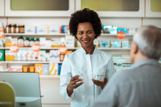 A smiling pharmacist advises a senior customer in a pharmacy