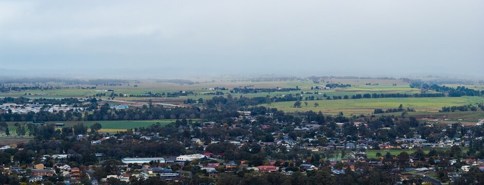 aerial view over distant country town houses of Singleton on overcast misty morning