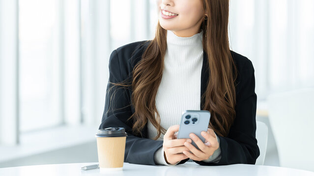 スマートフォンを使う笑顔の女性・ビジネスウーマン