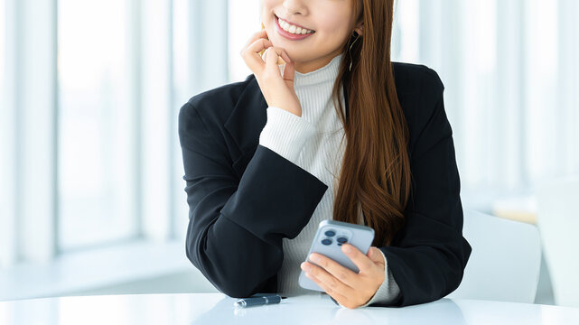 スマートフォンを使う笑顔の女性・ビジネスウーマン