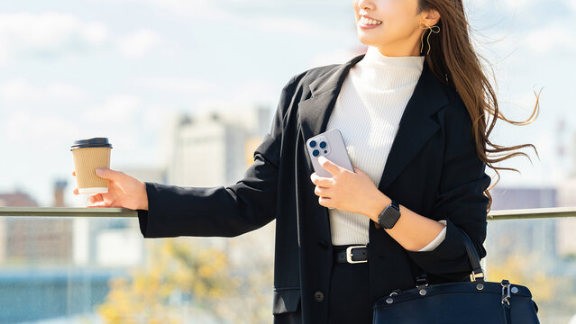 オフィス街でスマートフォンを持つ女性・ビジネスウーマン