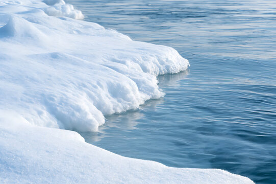 Arctic landscape with melting ice floes and clear blue sea water. Fresh snow and frozen nature scenery in cold polar climate. Global warming concept.