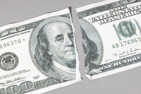 torn one hundred dollar banknote in half close up