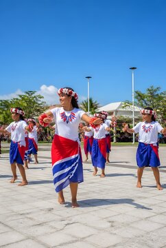 Young Women and Girls Perform Traditional Dance in Colorful Attire Under a Bright Blue Sky