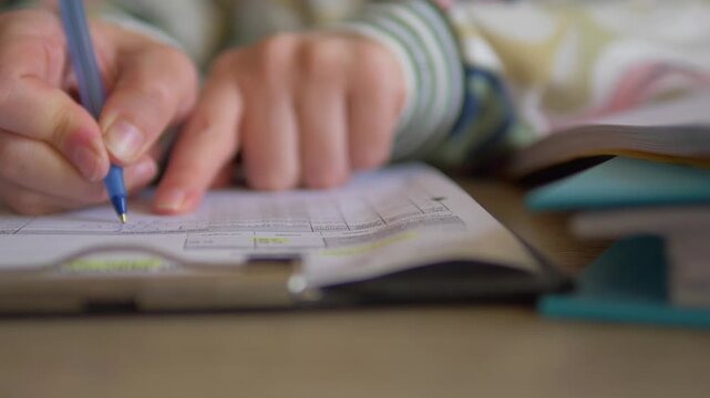 Auditor cross-referencing financial spreadsheet with pointing finger and taking notes - Close up of hands meticulously checking data on a clipboard form line by line