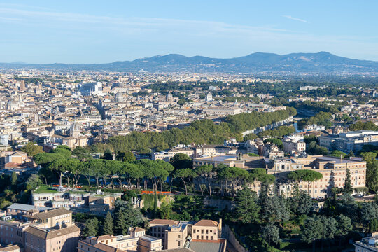 Aerial view of Rome rooftops, domes and Tiber river with pine trees and mountains from St Peter's Basilica