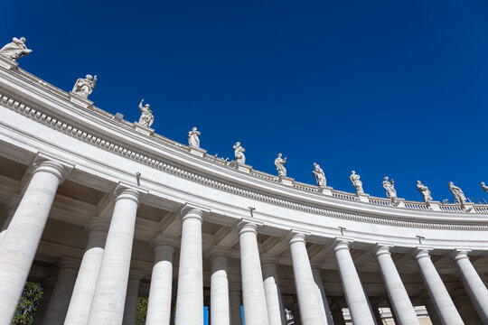 Bernini colonnade with statues of saints against deep blue sky in St. Peter's Square, Vatican City