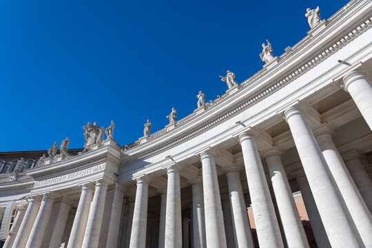 Bernini colonnade with statues against a deep blue sky in St. Peter's Square, Vatican City