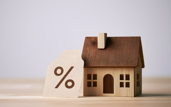 Miniature house with a percentage tag symbol representing mortgage interest rates and real estate investment
