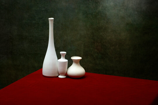 Still life with white vases on a table with a red tablecloth