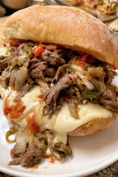 delicious mouthwatering artisan roast beef sandwich served on a fresh crusty bun loaded with melted mozzarella cheese grilled mushrooms sauteed onions and roasted red bell peppers closeup