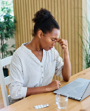 Portrait of a young black businesswoman havin a headache, or being stressed at work in the office. Overworked and sleepy frustrated business person