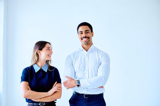 Business colleagues standing with crossed arms, smiling and sharing a confident moment, representing teamwork, trust and workplace success