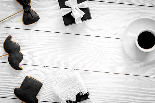 Birthday gift for men. Wrapped box, cookies in shape of black tie, mustache, hat. White background top view copyspace