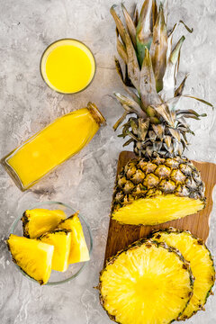 Non-alcoholic beverages. Bottle with fruit juice near pineapples slices on grey background top view