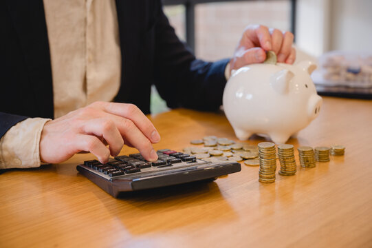 A man is putting coins into a piggy bank. Concept of saving money and being financially responsible. personal finance investment banking wealth financial planning