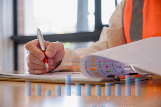 Engineer wearing safety vest working on documents and chart diagram of energy sustainability virtual wind turbine reduce co2 emission concept
