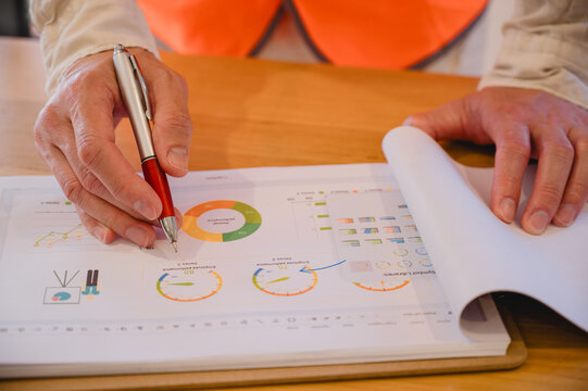 Business or engineer professional reviewing financial charts, performance metrics, and data visualizations with a pen, focusing on business analysis, strategic planning, corporate decision-making.