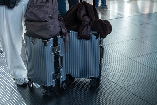 Two blue hard shell suitcases with backpack and brown fleece jacket at a train station in Rome, Italy