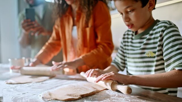 Family baking cookies together home kitchen. Close up boy rolling dough mother.