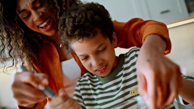 Son whisking eggs glass bowl with mom. Closeup hands mixing batter home kitchen.