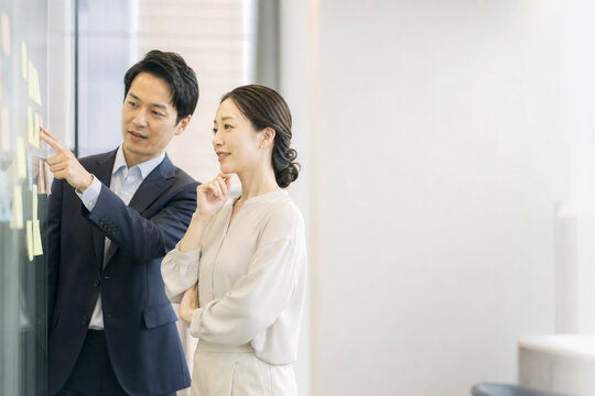 付箋を指しながら相談する日本人男女