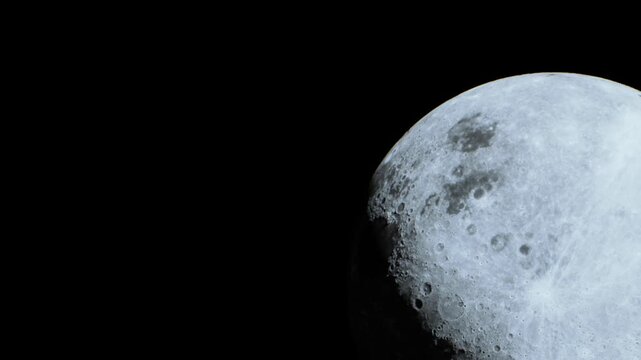 A close up of the moons surface taken at night. Craters and textures are visible. The black sky surrounds the moon, creating a sharp contrast.