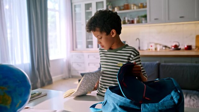 Mother bringing water bottle lunchbox. Boy packing school backpack home kitchen.