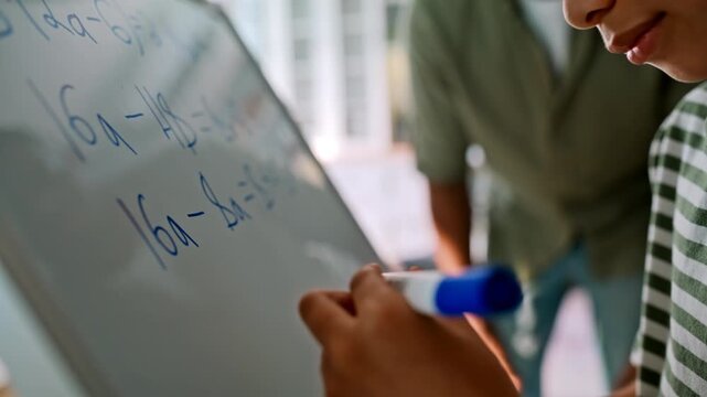 Closeup boy writing math answer whiteboard. Child solving algebra equation home.