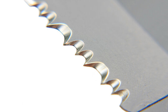 Detailed macro view of metal pocket knife blade showing sharp silver serrated edge pattern on white background