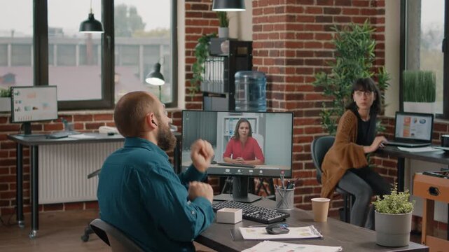 Videoconference, communication and planning as a businessman speaks with a woman on his desktop monitor from a modern office, for online meetings, collaboration and remote project discussion.